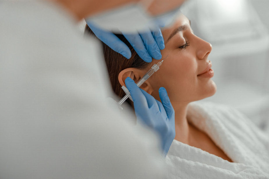 dark haired woman gets profhilo injection for skin rejuvenation with relaxed smile in clinic environment